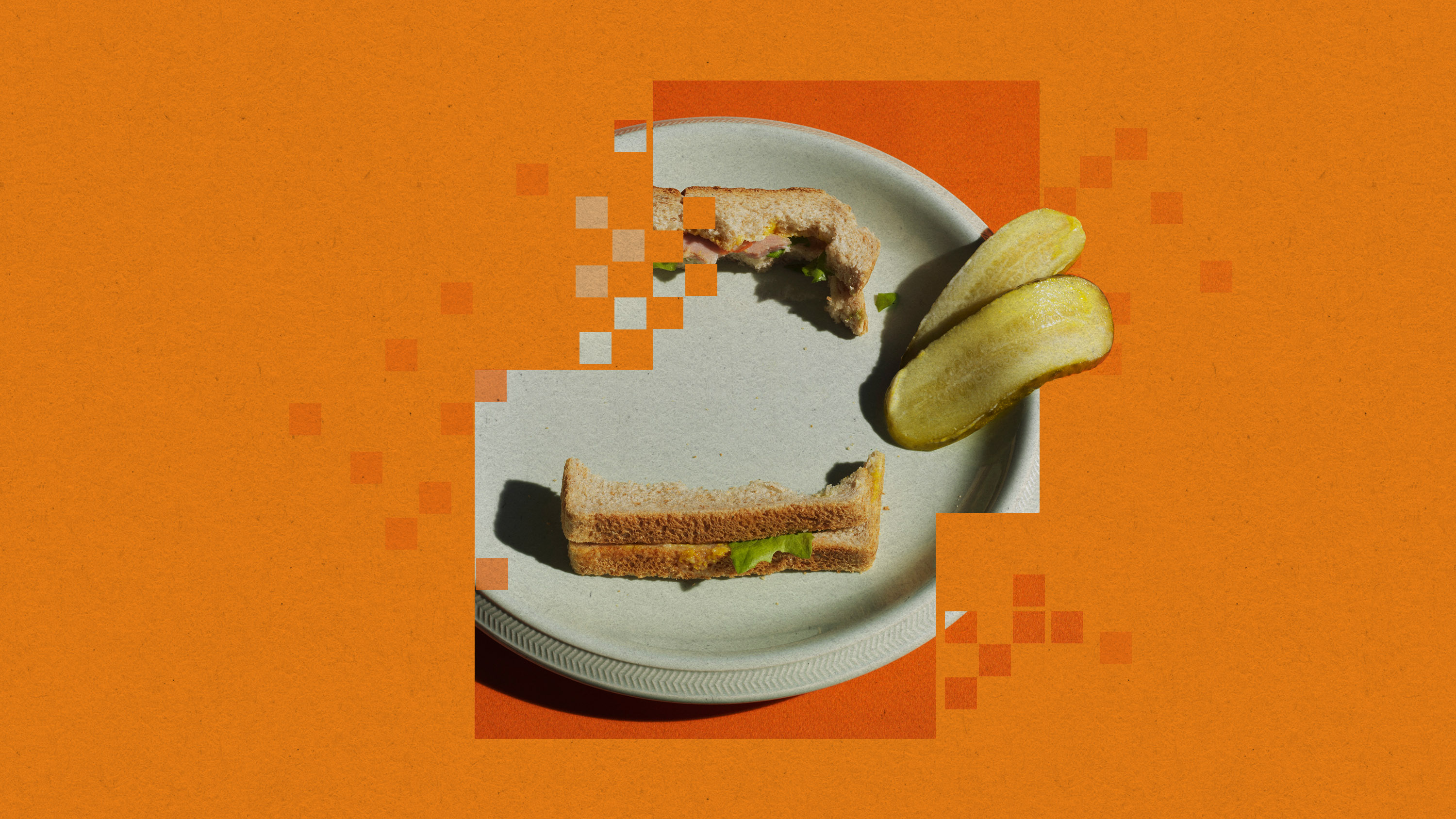 a pixelated plate with the crusts of a sandwich and two pickle slices