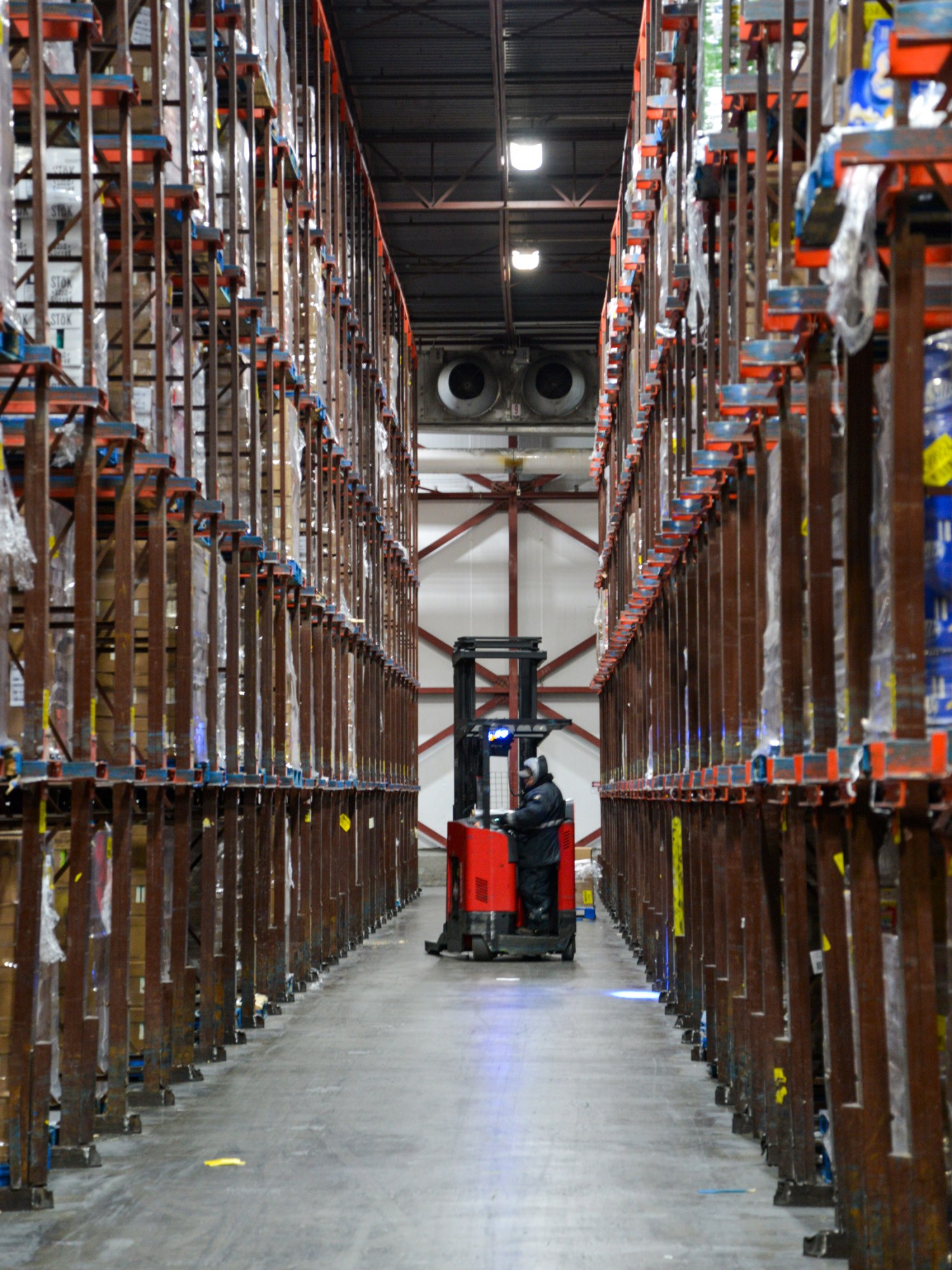 warehouse aisle with a man on a forklift at the far end