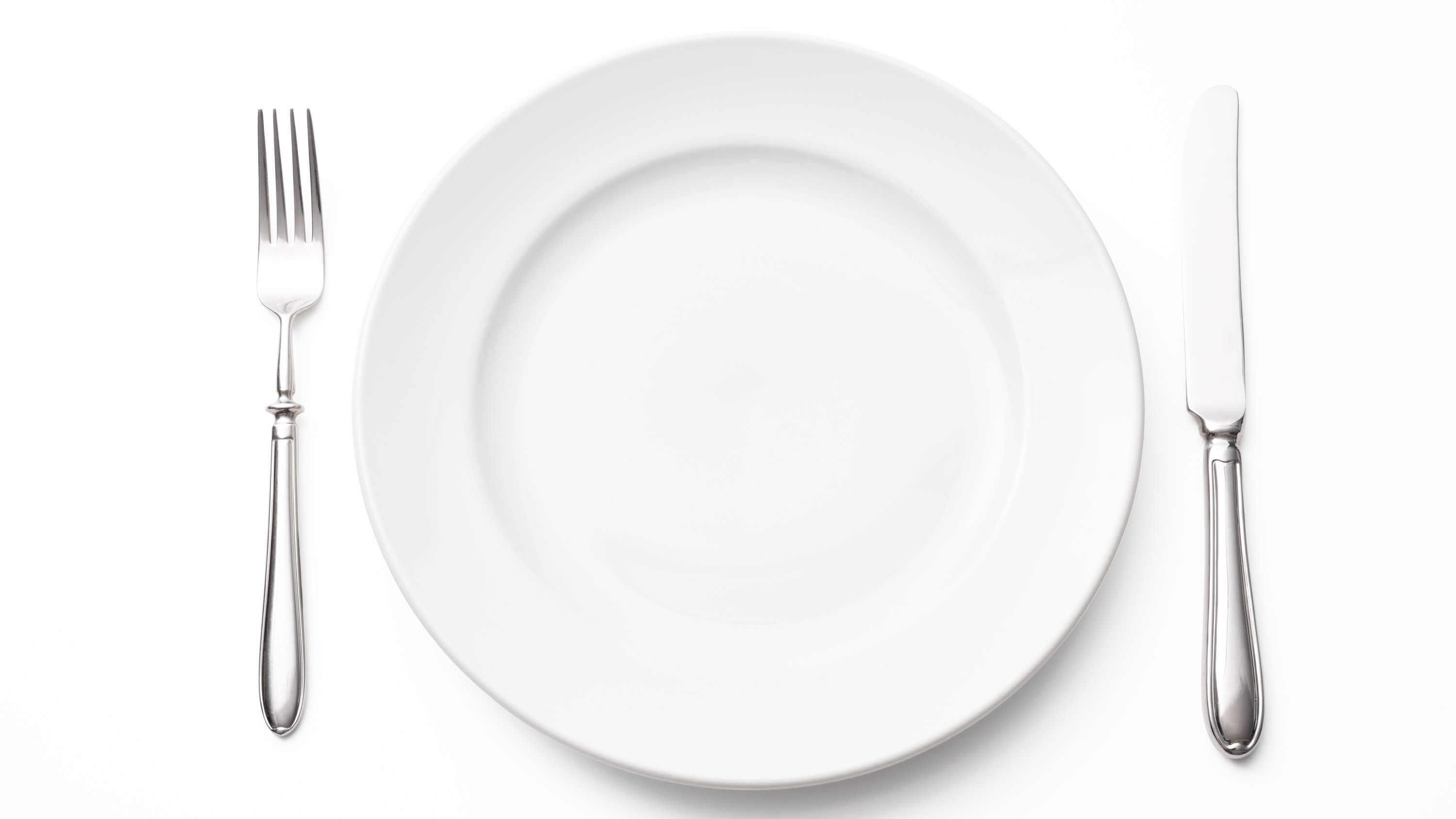 Overhead shot of white empty plate with silver knife and fork isolated on white background with clipping path.